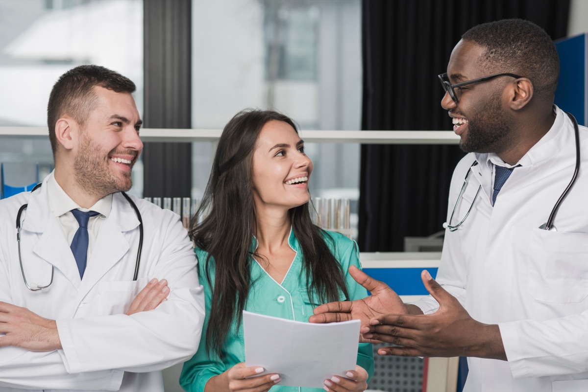 Three smiling clinicians reviewing a document together