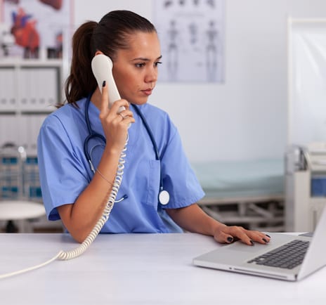 A nurse makes a follow-up call at her desk