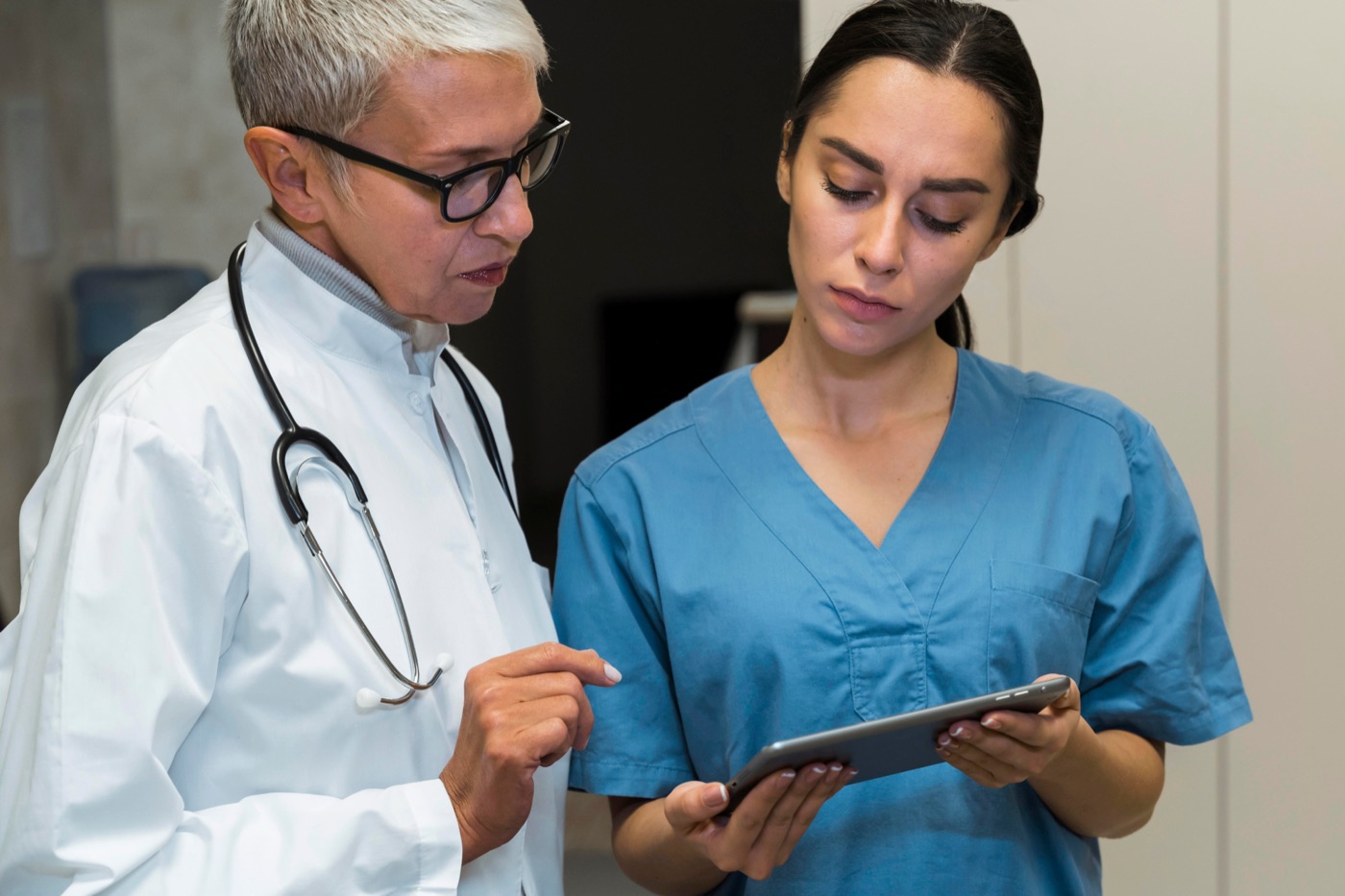A doctor and a nurse review a patient's notes on a tablet